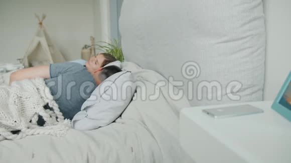 熟睡的男人醒来时看着智能手机微笑然后和妻子在床上打盹视频的预览图