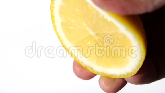 用手在白色背景上缓慢地挤压新鲜柠檬柠檬汁从果肉中排出并滴下视频的预览图
