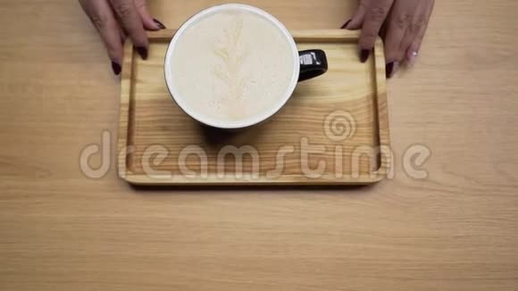 咖啡师女孩把一杯准备好的卡布奇诺咖啡放在杯子里给咖啡店的顾客视频的预览图