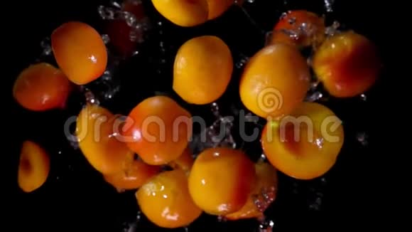 成熟的杏半部分正随着黑色背景上的水花飞起视频的预览图