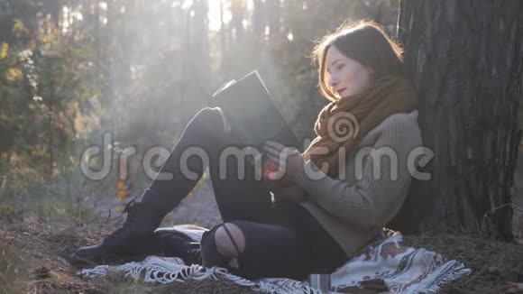 年轻快乐迷人的女旅行者坐在格子布上看书在外面放松怀旧女游客的乐趣视频的预览图