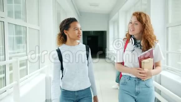 女孩朋友在学校大厅里散步拿着书聊天做着击掌视频的预览图