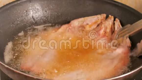 在黑锅里用鱼汁把炸好的鱼翻转热油沸腾了视频的预览图