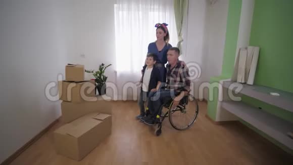 有残疾父亲坐轮椅的年轻家庭幸福地搬家讨论新公寓的家具安排视频的预览图