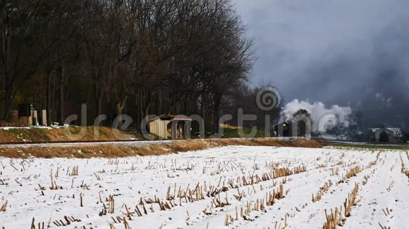 蒸汽机和乘用车沿阿米什农场土地在第一次下雪后视频的预览图