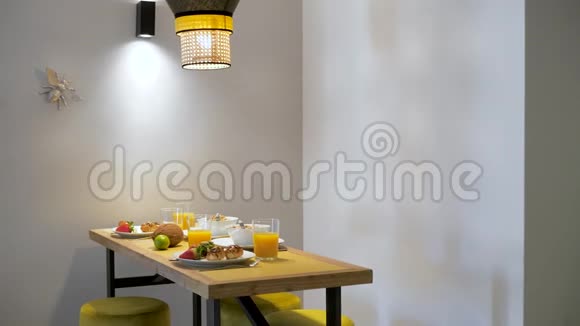 木制桌子上的食物被灯点亮玉米片新鲜草莓牛角面包和橙汁视频的预览图