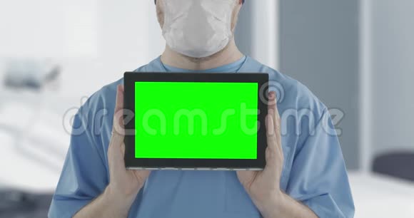 医生戴着医用口罩用绿色屏幕拍摄平板电脑阿尔法哑光便于图片或视频视频的预览图