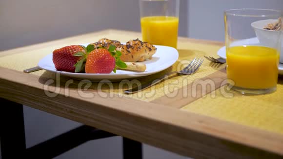 在家吃早餐新鲜草莓牛角面包和橙汁放在木桌上视频的预览图