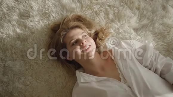 镜头接近年轻的白种人女人躺在柔软的床上阳光和微笑快乐女孩在室内休息视频的预览图