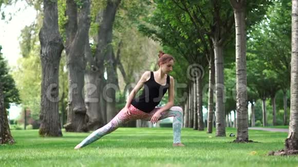 美丽的运动女孩在公园里慢动作练习瑜伽视频的预览图