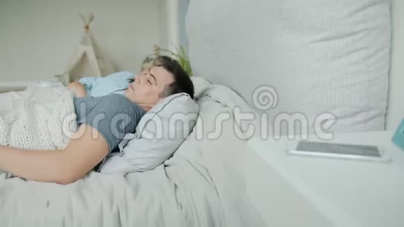 一个男人和妻子睡在床上然后使用智能手机放松地睡觉视频的预览图