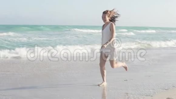 一个美丽的女人从她的脚上飞起沿着海滩奔跑视频的预览图