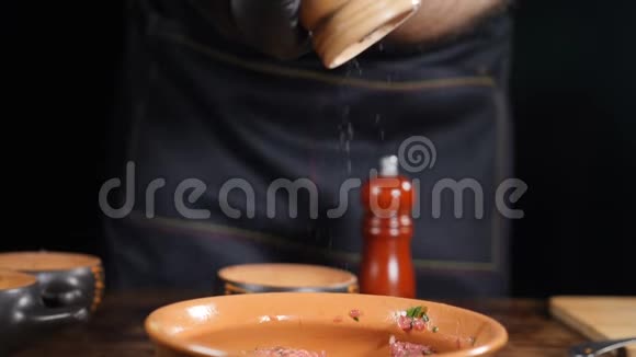 厨师的特写镜头用木磨将一些盐加入到盘子中盐在缓慢运动中下降用磨盐视频的预览图