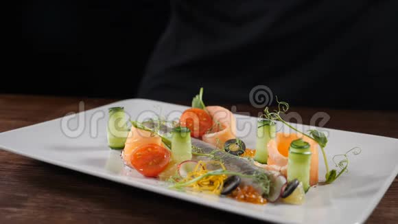 慢动作的食物镜头美味的鲱鱼切片配黄瓜和蔬菜厨师洒水视频的预览图