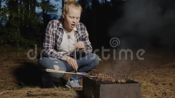 小女孩吃用烧烤火的木棍做的热棉花糖少女们烤棉花糖视频的预览图