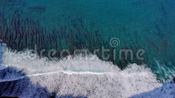 一个珊瑚礁在海岸的无人机上飞行的空中视频一股海浪冲击着巴厘岛海岸外的一个海洋暗礁视频的预览图