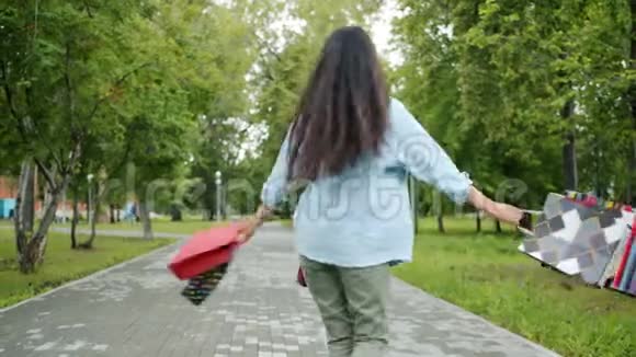 快乐的亚洲女孩在公园里旋转拿着购物袋玩得开心视频的预览图