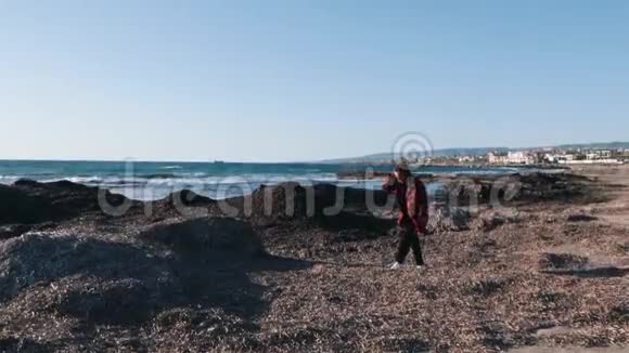 忧郁悲伤的女人穿着格子红色衬衫走在空海的岸边年轻孤独的女人一个人呆在海滩上悲观主义视频的预览图