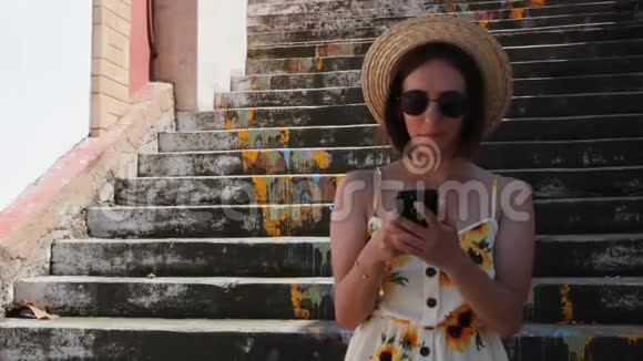 漂亮的黑发女人穿着向日葵站在楼梯边一边打电话一边微笑视频的预览图