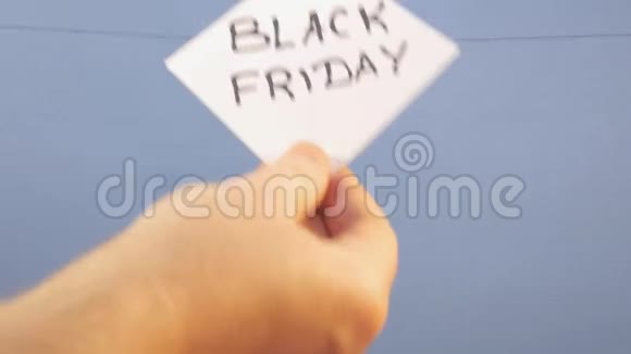 一个男人把一张白纸挂在蓝色背景上上面印着黑色星期五黑色铭文视频的预览图