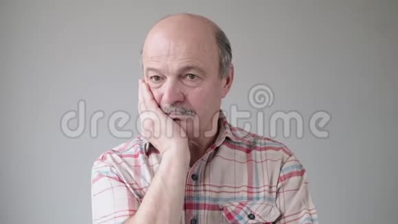 无聊的西班牙裔高级男子手握脸颊脸上有阴郁和悲伤的情绪视频的预览图