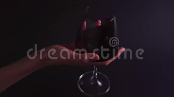 酒的味道一个女人手在黑色的背景上旋转一个杯子酒吧或餐馆的专业人士视频的预览图