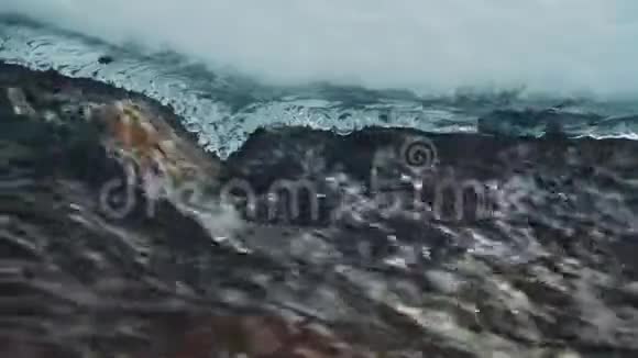 快速移动的水经过融化的冰特写镜头慢动作雪林中的溪流视频的预览图