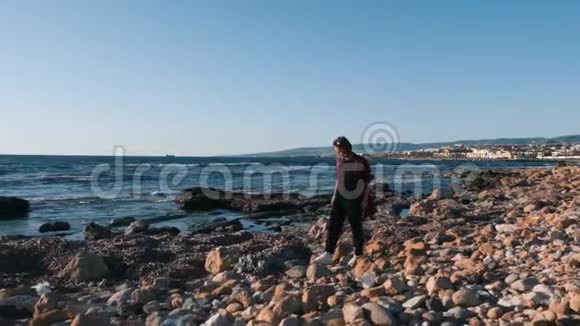 孤独忧郁的年轻女子走在空荡荡的鹅卵石海滩上年轻女子沿着污染的海滩散步伤心的女人走在人群中视频的预览图