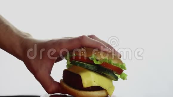 男性手从盘子里拿一个大汉堡大的多汁汉堡有牛肉切新鲜蔬菜和奶油奶酪青年视频的预览图