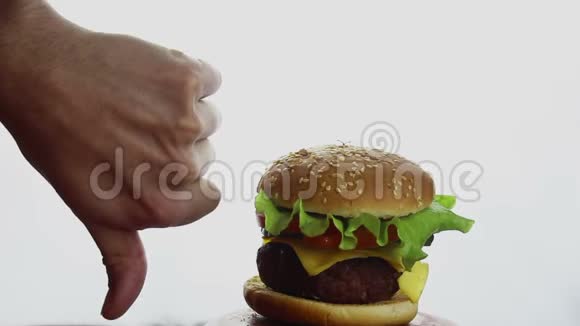 雄性手在新鲜多汁的汉堡的背景上显示拇指向下大型多汁汉堡和牛肉切新鲜蔬菜视频的预览图