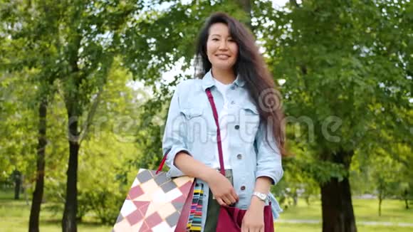 美丽的亚洲女孩微笑着站在公园里的照片视频的预览图