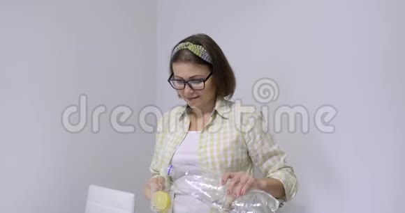 成熟的微笑女人从装有柠檬的瓶子里倒矿泉水视频的预览图