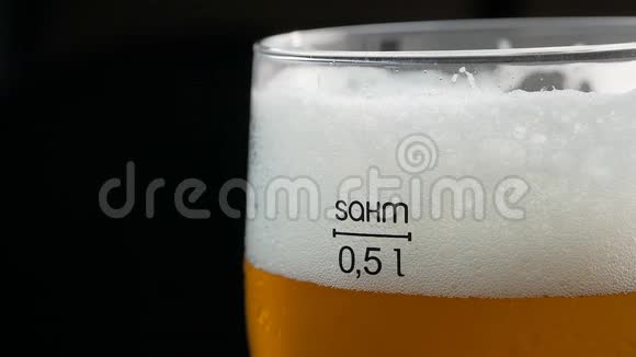 在深色背景下的玻璃杯中加入亮黄色啤酒视频的预览图