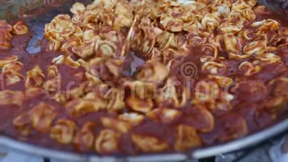 番茄酱中的美味烤馄饨用大煎锅煮熟视频的预览图
