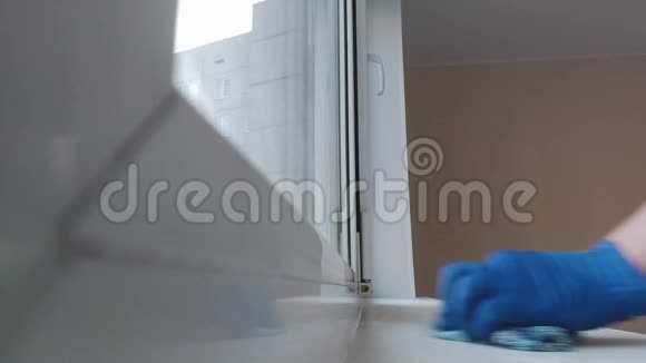 一个戴着蓝色橡胶手套的妇女在窗台上搓抹布打扫房间视频的预览图