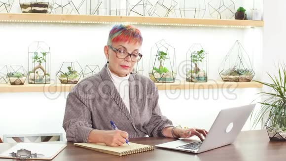 漂亮的商务女性留着五颜六色的短发戴着眼镜穿着笔记本电脑的夹克视频的预览图
