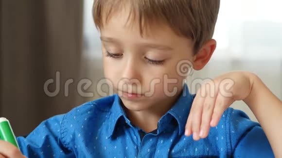 一个小男孩坐在桌边画一个亮绿色的记号笔体贴的孩子的脸视频的预览图