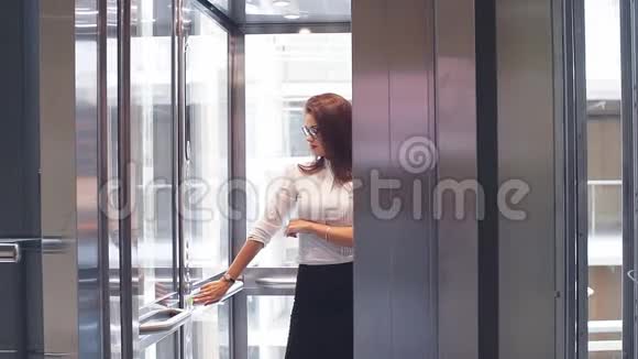 戴眼镜的性感商务女士在现代办公大楼里使用电梯视频的预览图