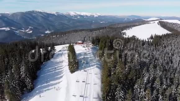 滑雪场上有滑雪者和滑雪升降机的空中滑雪斜坡雪山森林视频的预览图