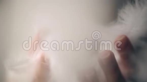 年轻女子用手吹着白色羽毛慢镜头视频的预览图
