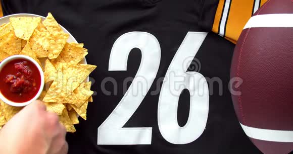 人们在一件26号的黑色运动衫和足球上吃带有温和萨尔萨的有机玉米片视频的预览图