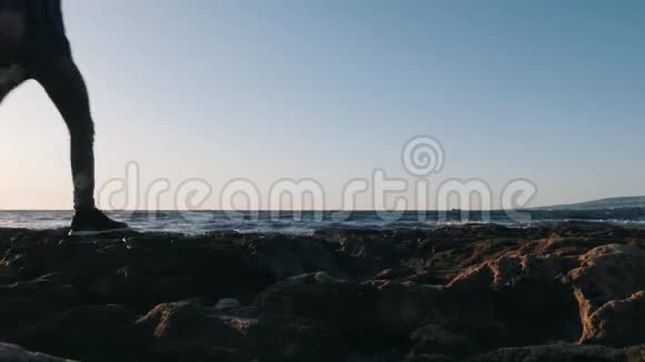 恋爱中的年轻夫妇沿着岩石海岸散步可爱的家伙他的女孩站在海边拥抱看着远方哈视频的预览图