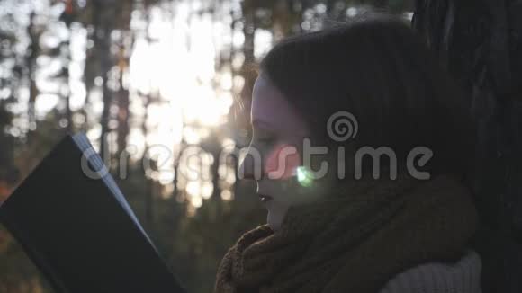 美丽的白种人美丽的女性旅行者在落日的秋天森林公园读书的画像视频的预览图