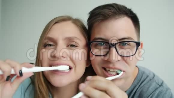 家庭幸福的慢动作男人和女人刷牙在浴室里玩得开心视频的预览图
