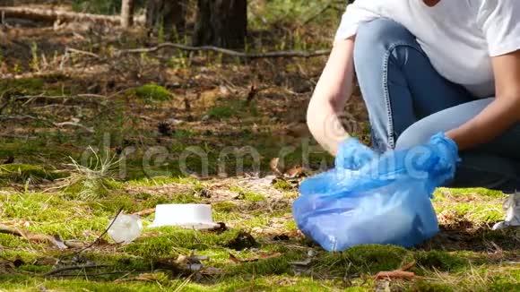 戴手套的女人的手女孩志愿者收集垃圾放进一个可生物降解的袋子视频的预览图