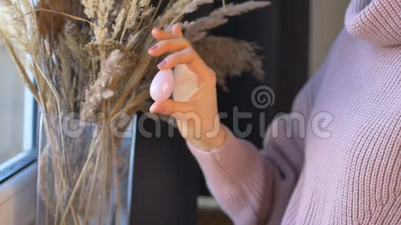 女孩手里拿着玫瑰石英石做的鸡蛋在小穗的背景上女性健康概念vumfitimbuilding视频的预览图