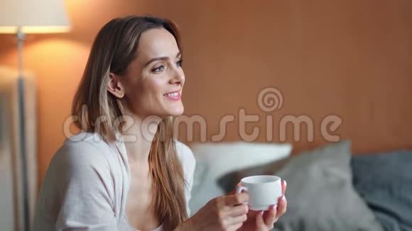 吸引人的愉快的女士在公寓放松喝热饮料享受有趣的中型特写镜头视频的预览图