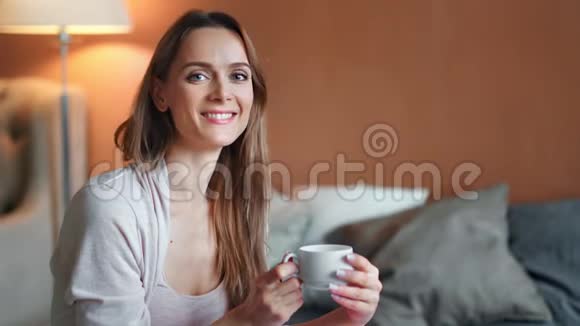 一幅美丽的早晨女人微笑着在卧室摆姿势的画像上面有一杯香水饮料视频的预览图