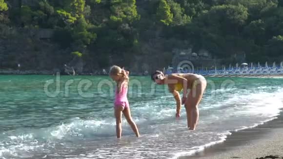 母亲和女儿在海滩附近的水里玩耍视频的预览图