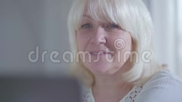 漂亮成熟的白种人女人的特写脸看着笔记本电脑屏幕微笑着快乐女性退休者视频的预览图